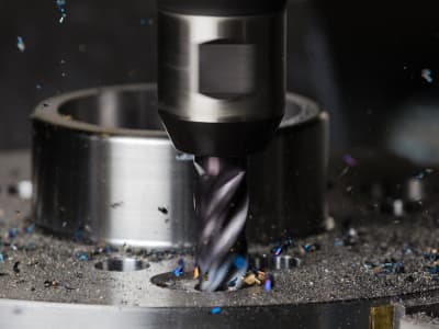 Eine Fräsmaschine bearbeitet ein Metallwerkstück mit hoher Präzision. Metallspäne sammeln sich um den Fräskopf und zeigen den Arbeitsfortschritt.
