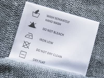 Detailaufnahme einer Waschanleitung von einem grauen Kissenbezug