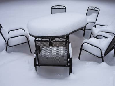 Eine Gartensitzgruppe mit einem Tisch und Stühlen aus Metall, die im Freien steht und mit Schnee bedeckt ist