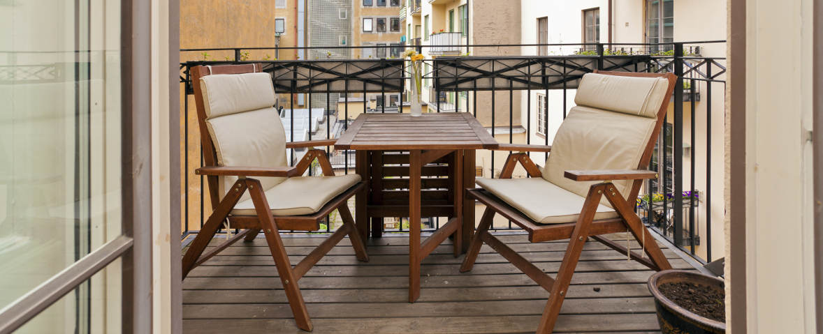 Foto von einem Balkon mit einem Klapptisch und zwei Klappstühlen aus Holz