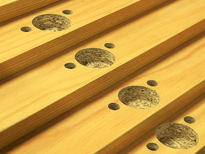 Nahaufnahme mehrerer Holzplatten mit präzise ausgefrästen Topfscharnier-Bohrungen. Die runden Vertiefungen dienen zur Montage von Scharnieren an Schranktüren