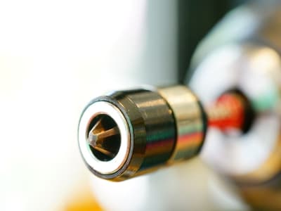 Das Bild zeigt eine Nahaufnahme eines Bohrfutters mit eingespanntem Bit in einem Akkuschrauber. Die glänzenden Metallteile sind scharf fokussiert.