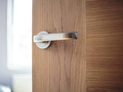 Detailaufnahme einer silbernen Türkinke an einer Holztür