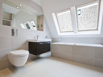 Ein modernes Badezimmer mit Dachschräge, großer Spiegelfläche, Hänge-WC, Waschbecken und Badewanne unter dem Fenster