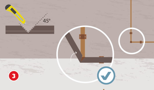 Eine schematische Darstellung zeigt das Isolieren eines gebogenen Heizungsrohrs mit einer einzigen Isolierschale. Die Schale wird mit einem Cuttermesser an zwei Stellen im 45°-Winkel eingeschnitten und an der Biegung zusammengefaltet. Ein Vergrößerungskreis zeigt die passgenaue Ausführung der Schnitttechnik. Ein Häkchensymbol markiert die korrekte Umsetzung. Unten links ist ein roter Kreis mit einer weißen 3