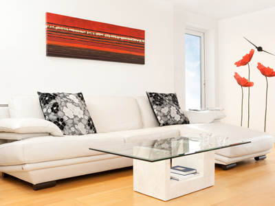 Eine moderne Infrarotheizung im Streifen-Design hängt über einem weißen Ledersofa in einem hellen Wohnzimmer