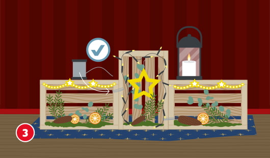 Eine schematische Darstellung zeigt drei unterschiedlich große Holzkisten, die zu einer weihnachtlichen Dekoszene kombiniert wurden. Die Kisten sind mit Tannenzweigen, Eukalyptus, Orangenscheiben, Lichterketten und Sternen dekoriert. Eine Laterne steht rechts, eine Sternenlichterkette verläuft über die Kisten. Ein Häkchensymbol markiert die korrekte Anordnung. Unten links ist ein roter Kreis mit einer weißen 3