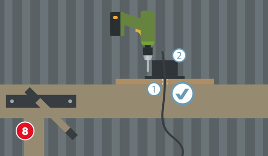 Eine schematische Darstellung zeigt die Montage einer Lampenfassung auf der Bodenplatte einer Gartenlampe. Die Fassung wird mit einer Schraube fixiert, das Stromkabel ist bereits eingeführt. Eine Bohrmaschine dient zum Verschrauben auf der Werkbank. Unten links ist ein roter Kreis mit einer weißen 8