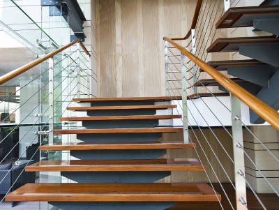 Moderne Holztreppe mit Edelstahlgeländer und Glaswänden in einem hellen Innenraum