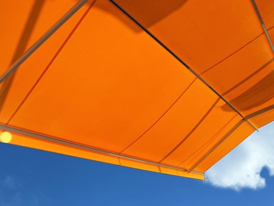 Blick von unten auf eine ausgefahrene, orangefarbene Markise