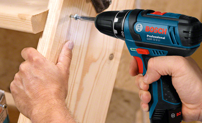 Jemand schraubt mit einem kleinen Akkuschrauber ein Holz Regal fest