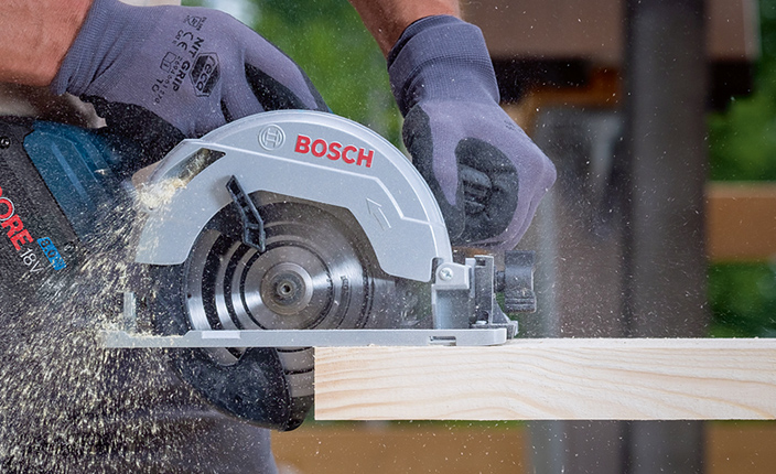 Jemand schneidet mit einer Bosch Säge Holz durch