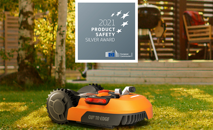 Ein Rasenmähroboter auf einer Wiese mit einem Product Safety Auszeichnung dadrüber