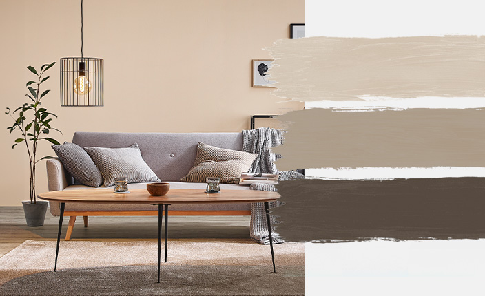 Ein gemütlich eingerichtetes Wohnzimmer mit beiger Wandfarbe, grauem Sofa und natürlichen Holzakzenten. Daneben drei Farbstreifen in Sandtönen und dunklem Braun zur Farbpalette „Cosy Sand“