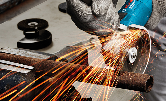 Jemand sägt ein Stahlrohr mit einem Bosch Winkelschleifer durch