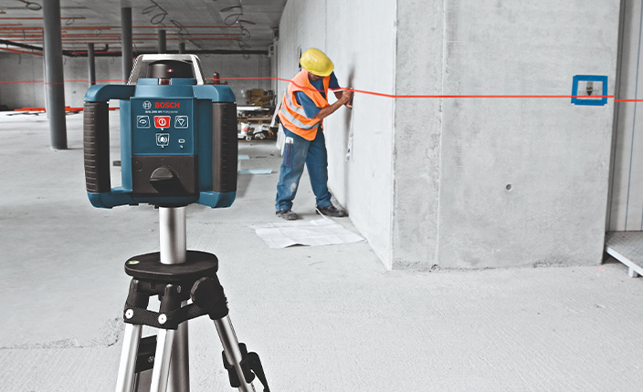 Jemand zeichnet eine Linie an eine Wand und verwendet zur Hilfe Vermessungstechnik von Bosch