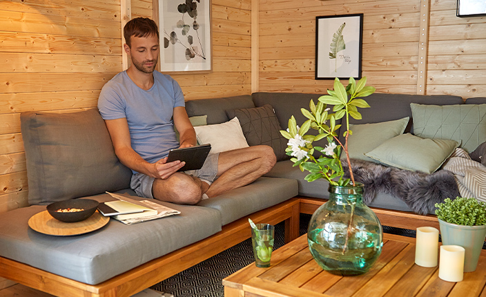 Ein Mann sitzt aufeinem Sofa in einer Holz Hütte