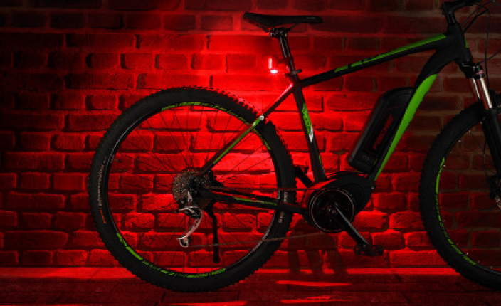 Fischer Fahrrad steht an einer Hauswand mit rotem Licht dran