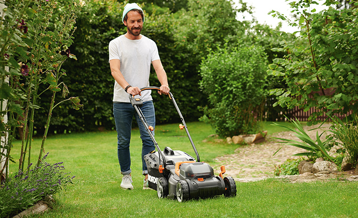 Ein Mann mäht Rasen in einemgrünen Garten