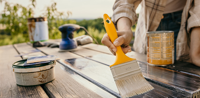 Ein Gartentisch der mit einer Holzlasur bestrichen wird