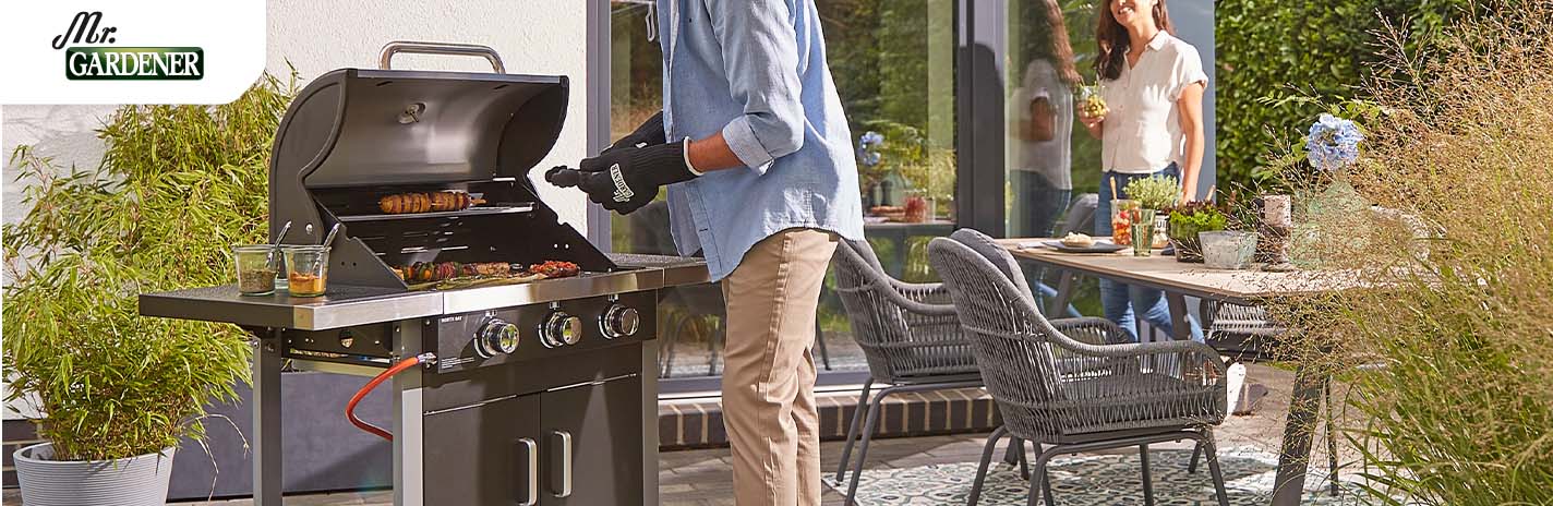 Ein Mann und eine Frau grillen in einem GArten mit einem Grill von einem Mr. Gardener Grill