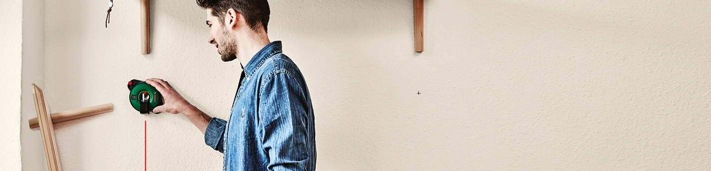 Ein Mannverwendet Messtechnik von Bosch an einer Wand