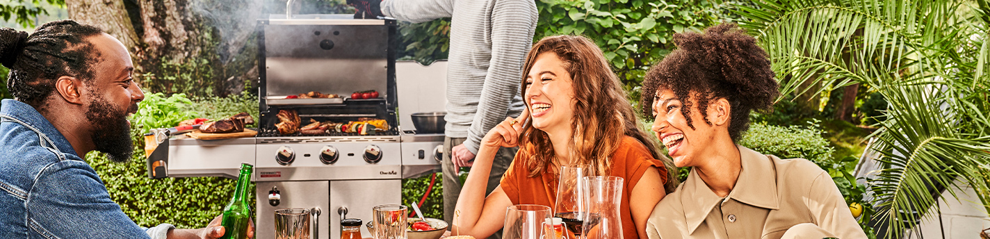 Vier Leute habenspaß bei einem Grillfest mit einem Grill im Hintergrund  von Char-Broil