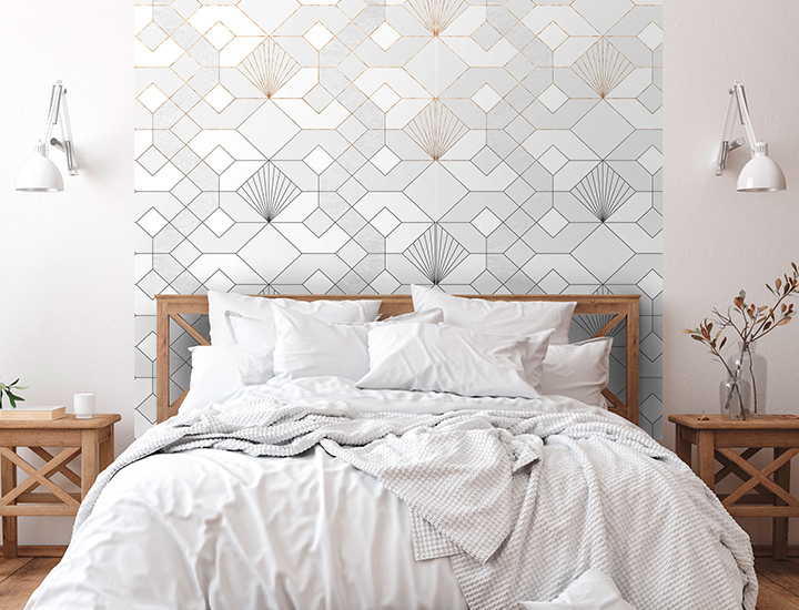 Schlafzimmer mit weißem Bett, geometrischer Tapete in Schwarz-Weiß als Wandakzent und zwei Nachttischen aus Holz mit Dekoobjekten.