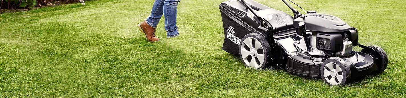 Jemand meht einen grünen Rasen mit einem schwarzen Rasenmäher von Mr.Gardener