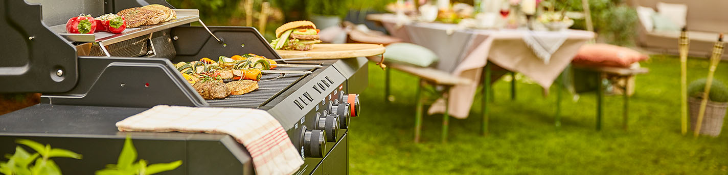 Ein Grill von der Marke Mr.Gardener mit essen drauf und einem Tisch im Hintergrund