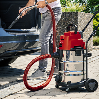 Jemand saugt sein Auto mit einem Einhell Staubsauger