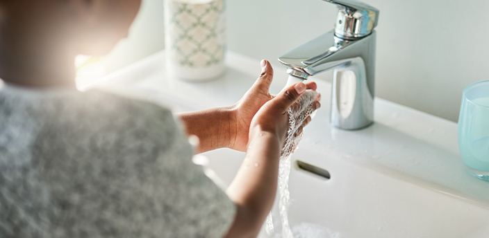 Kind wäscht sich die Hände unter einer modernen Badarmatur