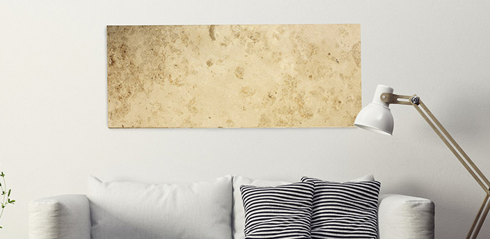 Flache Infrarotheizung in Steinoptik an der Wohnzimmerwand über einem Sofa mit Kissen und Leselampe