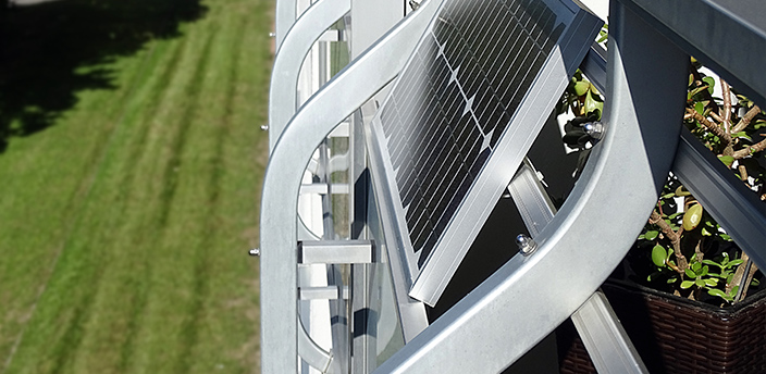 Balkonkraftwerk mit Solarpanel, das an einem Metallgeländer montiert ist.