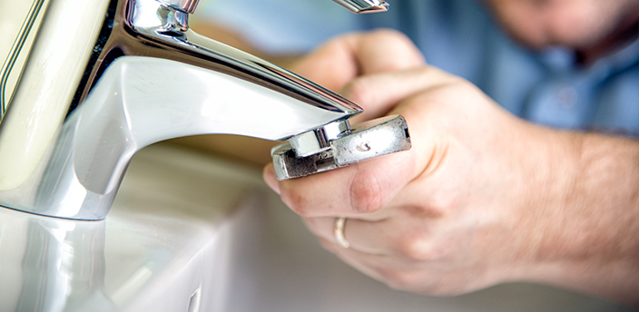 Nahaufnahme eines Mannes, der einen Wassersparstrahler an einen Wasserhahn montiert