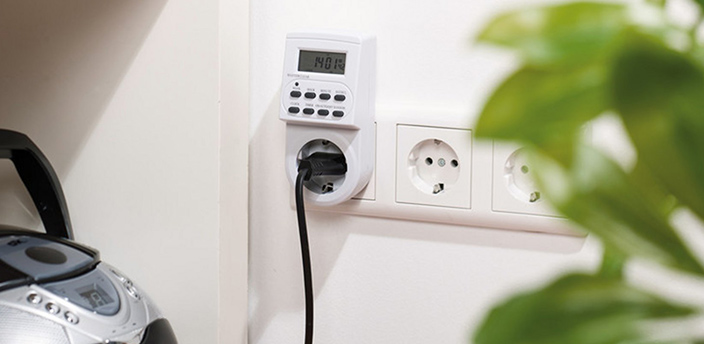 Digitale Zeitschaltuhr in der Steckdose steuert den Stromfluss eines angeschlossenen Geräts.