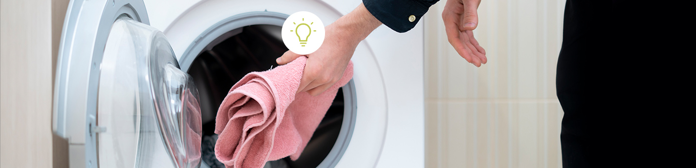 Hand steckt rosa Handtuch in die Trommel einer Frontlader-Waschmaschine. Rechts im Bild steht in grün: „ENERGIESPARTIPPS ZUM STROM SPAREN“. Darunter in schwarz: „Wir zeigen Dir die größten Stromfresser in Deinem Haushalt.“ Unten rechts befindet sich ein grüner Button mit weißer Schrift: „JETZT ENTDECKEN“.