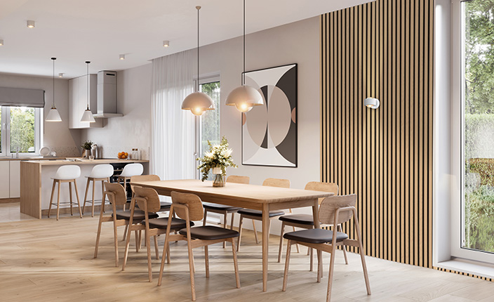 Offener Küchenbau mit Übergang zum Esszimmer; ein hölzener Tisch mit den dazupassenden Stühlen, im Hintergrund eine weiße Kücheninsel mit drei Hockern