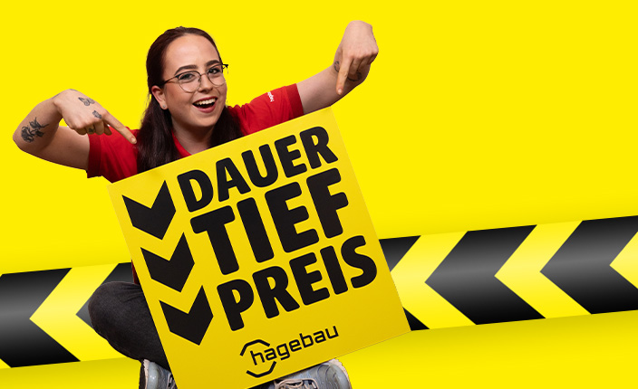 Marktmitarbeiterin, die mit beiden Fingern auf ein Schild zeigt, auf dem Dauertiefpreis steht.