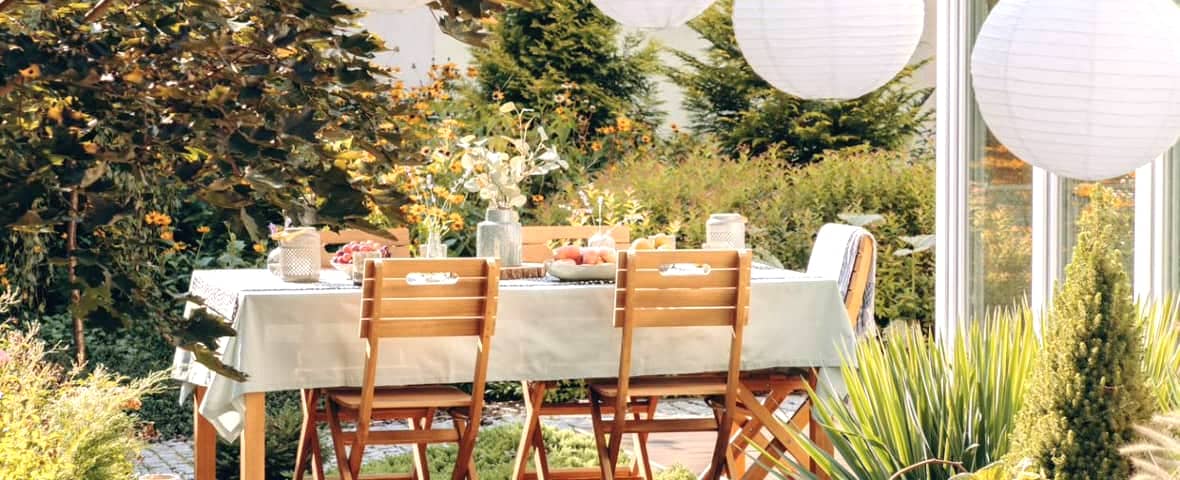 gedeckter Tisch mit Stühlen im Garten