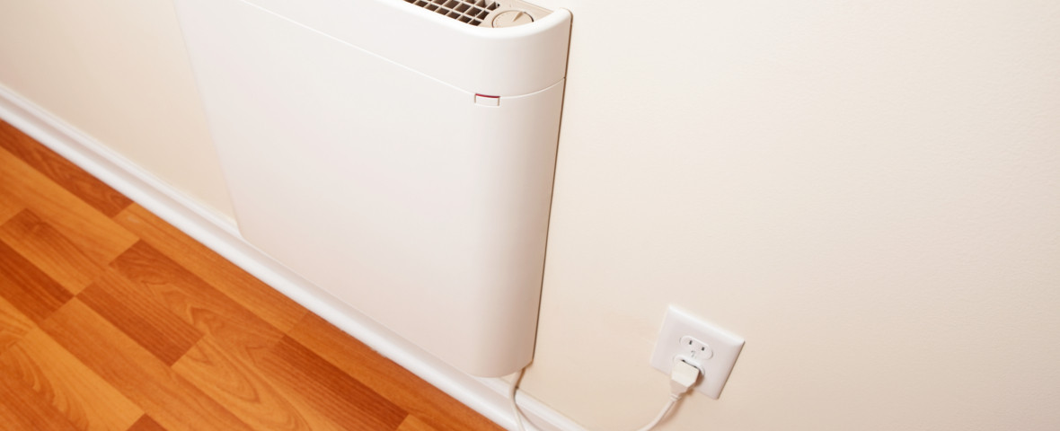 Ein weißer elektrischer Konvektor ist an der Wand montiert und über ein Kabel mit der Steckdose verbunden