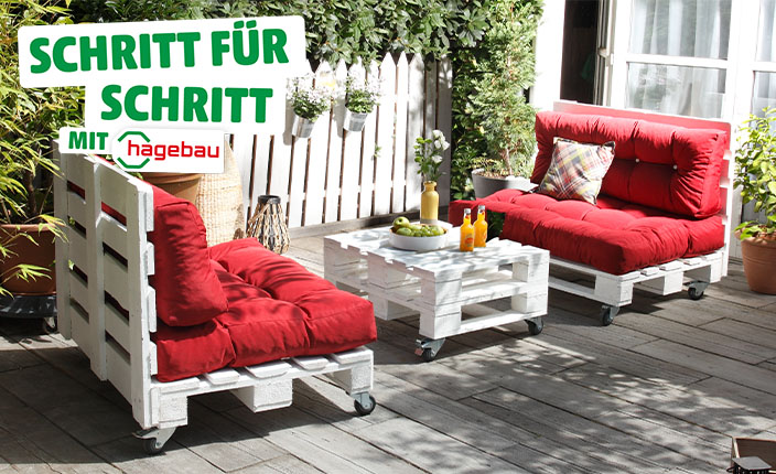Gartenmöbel aus weißen Paletten mit roten Polstern und Rollen, bestehend aus zwei Sitzbänken und einem Tisch, auf einer Terrasse mit Pflanzen und Getränken. Text: "Schritt für Schritt mit hagebau".