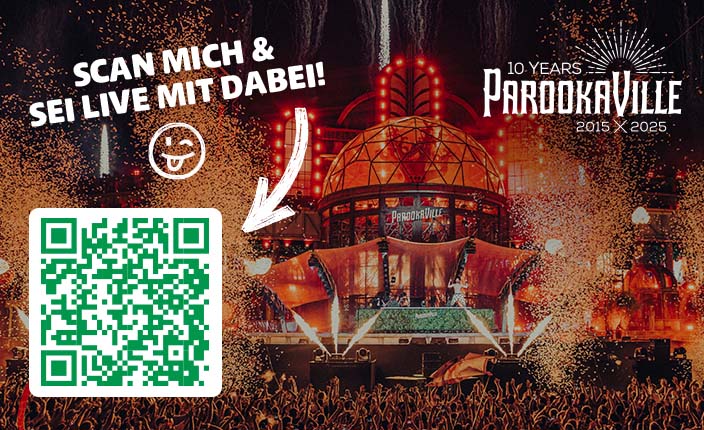 Eine große Menschenmenge feiert auf dem PAROOKAVILLE-Festival vor einer Bühne mit vielen Lichtern und Feuerwerk.